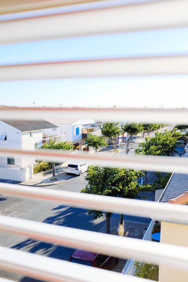 a view through window blinds of a mediterranean street