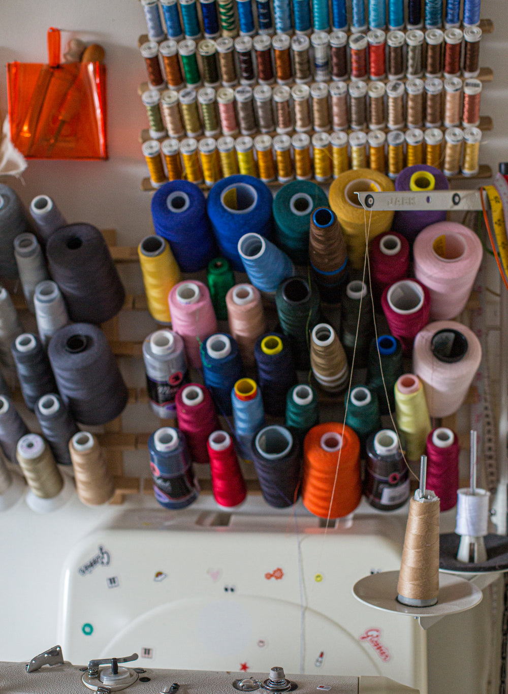 a wall with spools of thread on a wooden rack