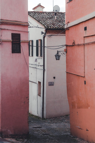 a white building between two pink buildings