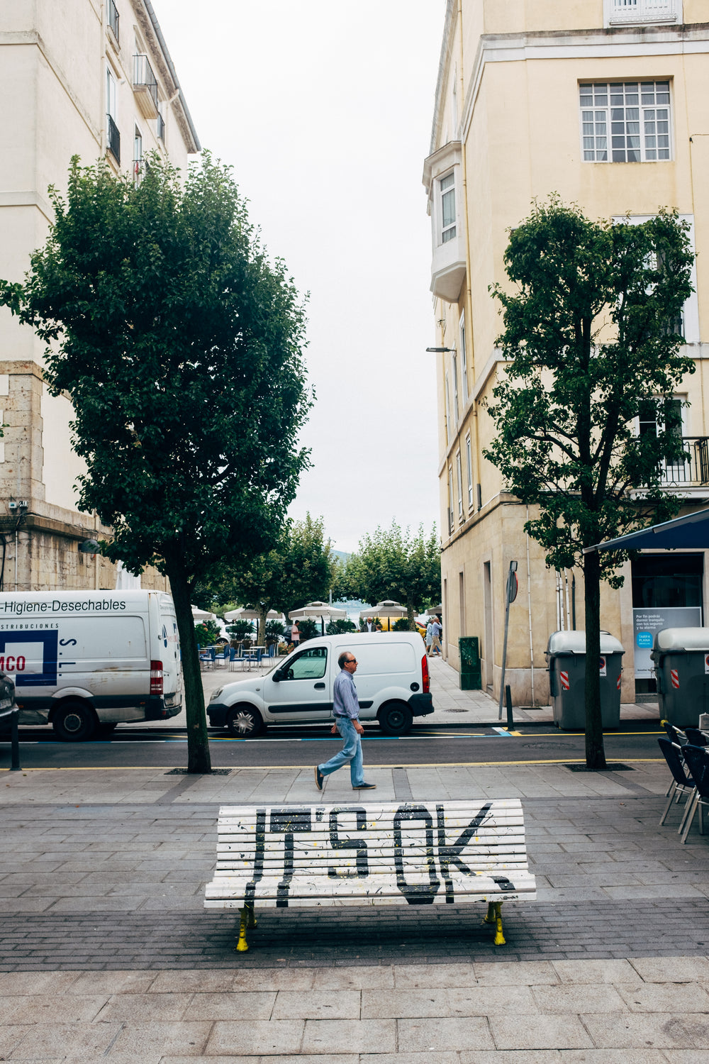 a white city bench has "it's ok" painted in black over it