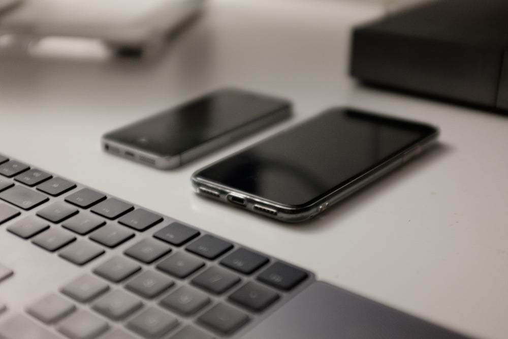 a white table with two cell phones and a keyboard