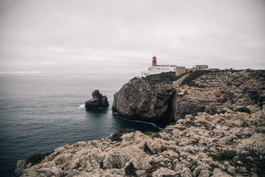 a white-wash lighthouse stands on a craggy cliff