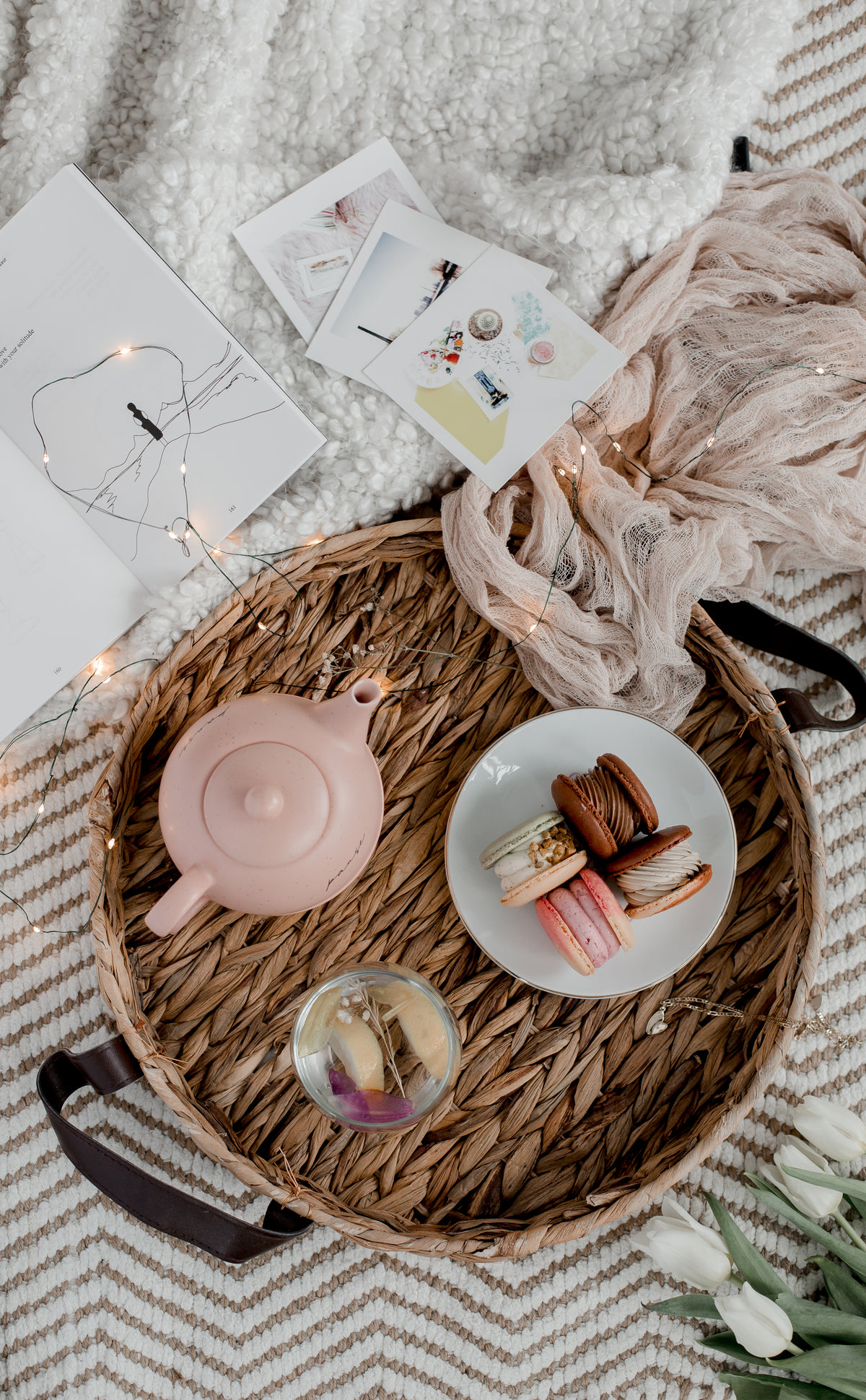 a wicker tray with macarons and a pot of tea