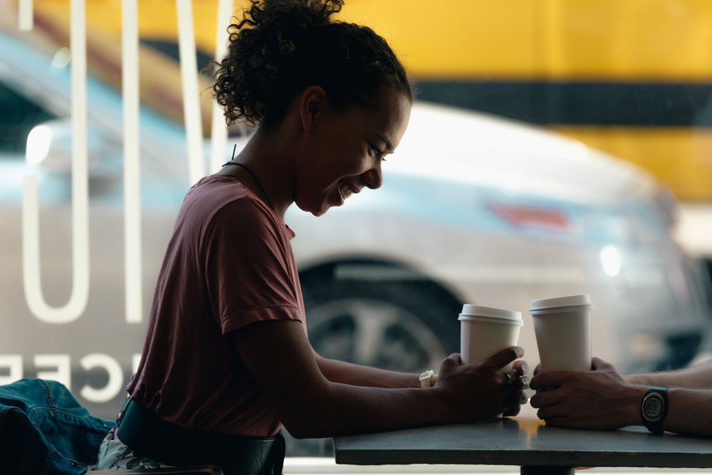 a woman and a man enjoy a laugh over coffee