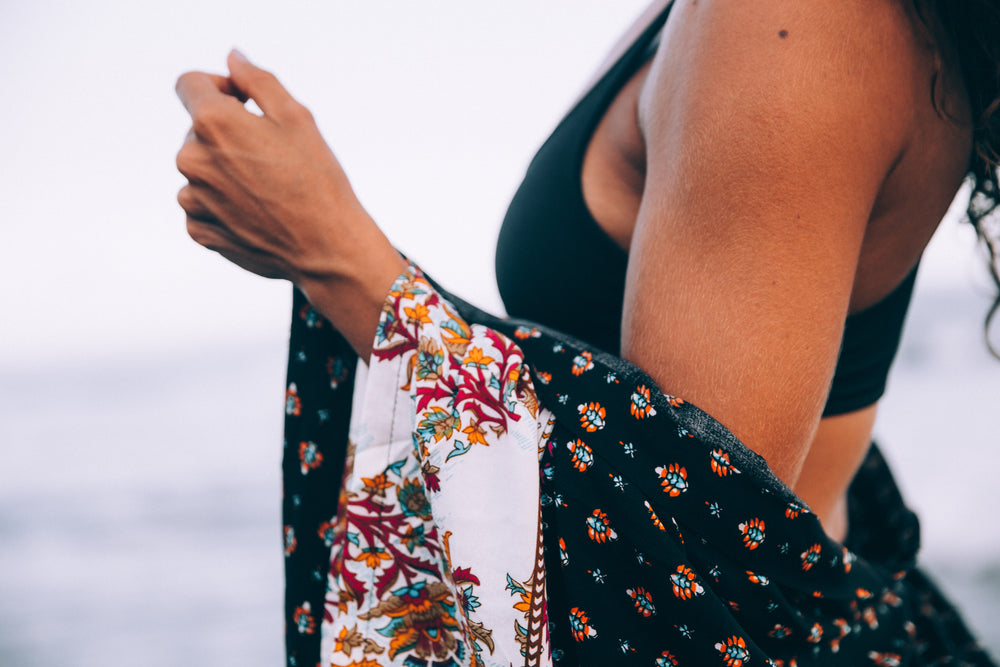 a woman at the beach with patterned shawl around her shoulders