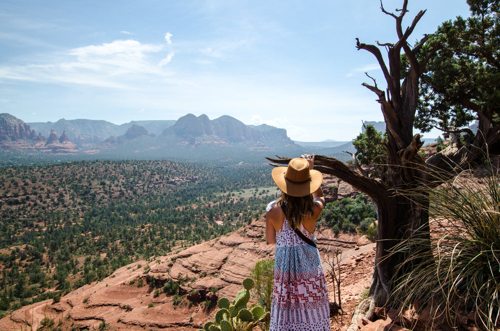 a woman by a tree looks down over valley