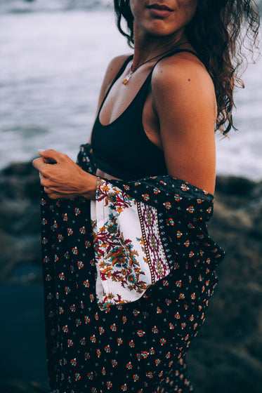 a woman by the sea with patterned shawl draped through arms