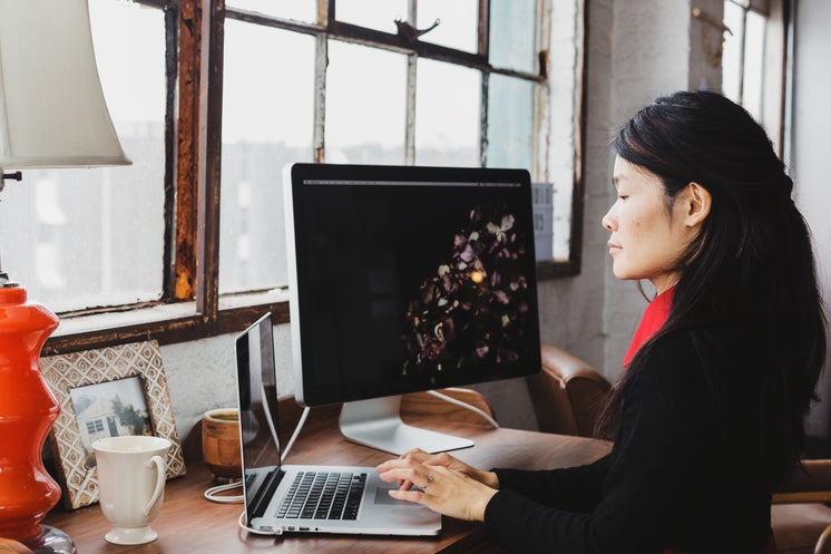 A Woman Immersed In Her Laptop And Monitor