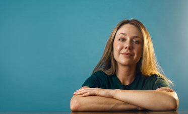 a woman in a plain green shirt against a blue backdrop