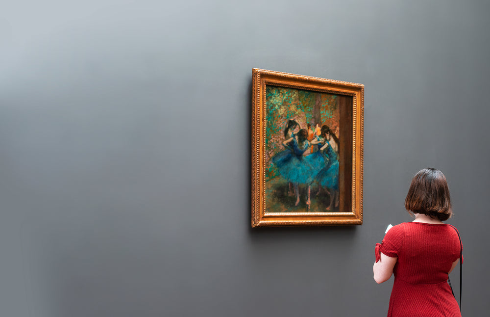 a woman in an art gallery ponders a degas painting