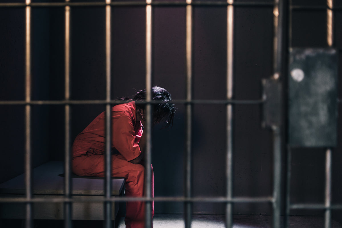 一个穿着橙色连体衣的女人坐在牢房里