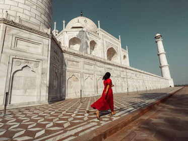 a woman in red passes the taj mahal
