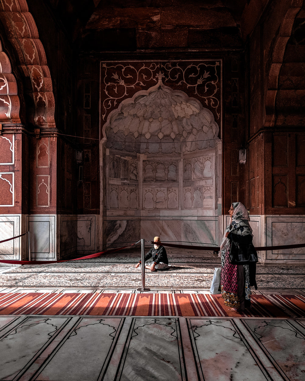 a woman in red walks through arched hall