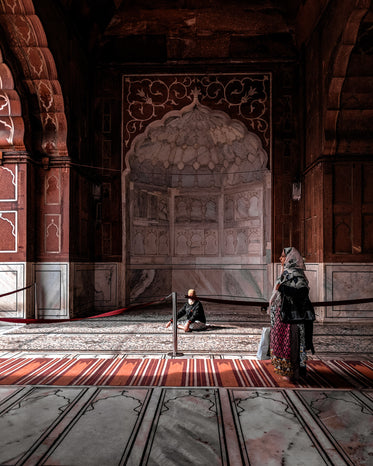 a woman in red walks through arched hall