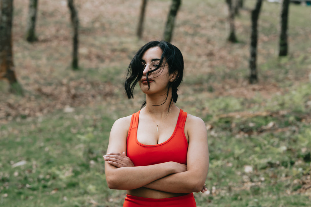 a woman in vibrant red top crosses her arms