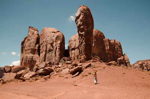 a woman looks up at stubby stone fingers of desert mountains