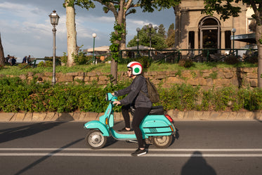 a woman on a turquoise moped on a highway