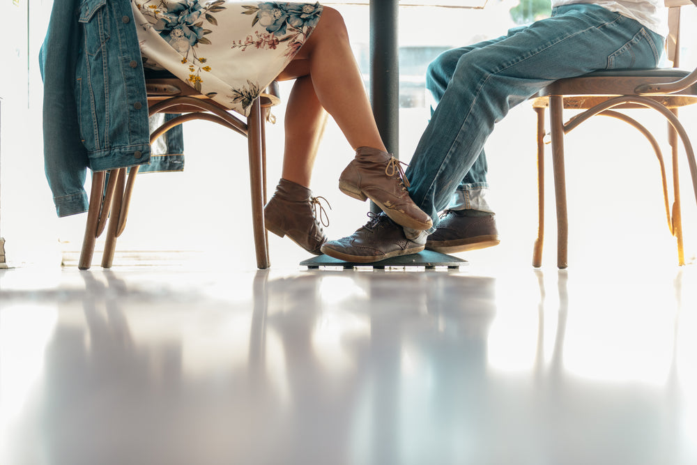 a woman plays footsie with a man in a cafe