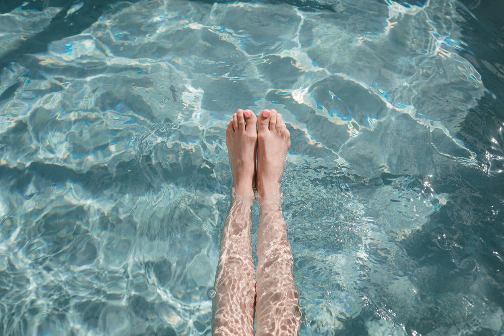 mulher estica os dedos dos pés enquanto relaxa na piscina