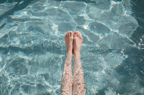 mulher estica os dedos dos pés enquanto relaxa na piscina