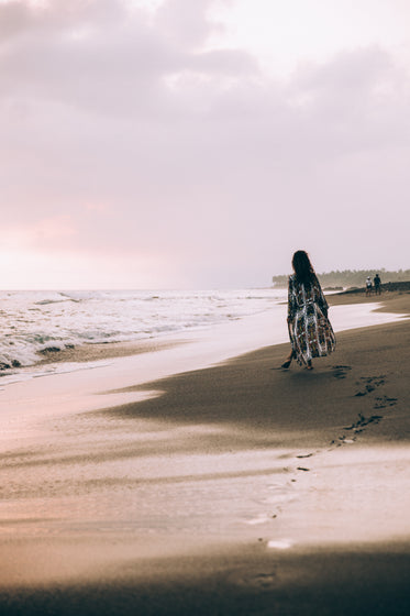 a woman poses with anklet on rocky beach