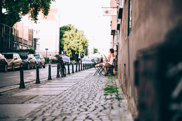 a woman reads a newspaper outside a cafe