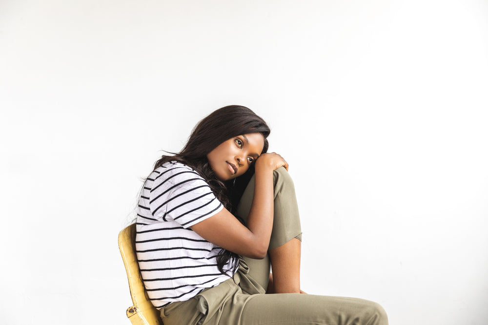 a woman rests head on knee and stares thoughtfully