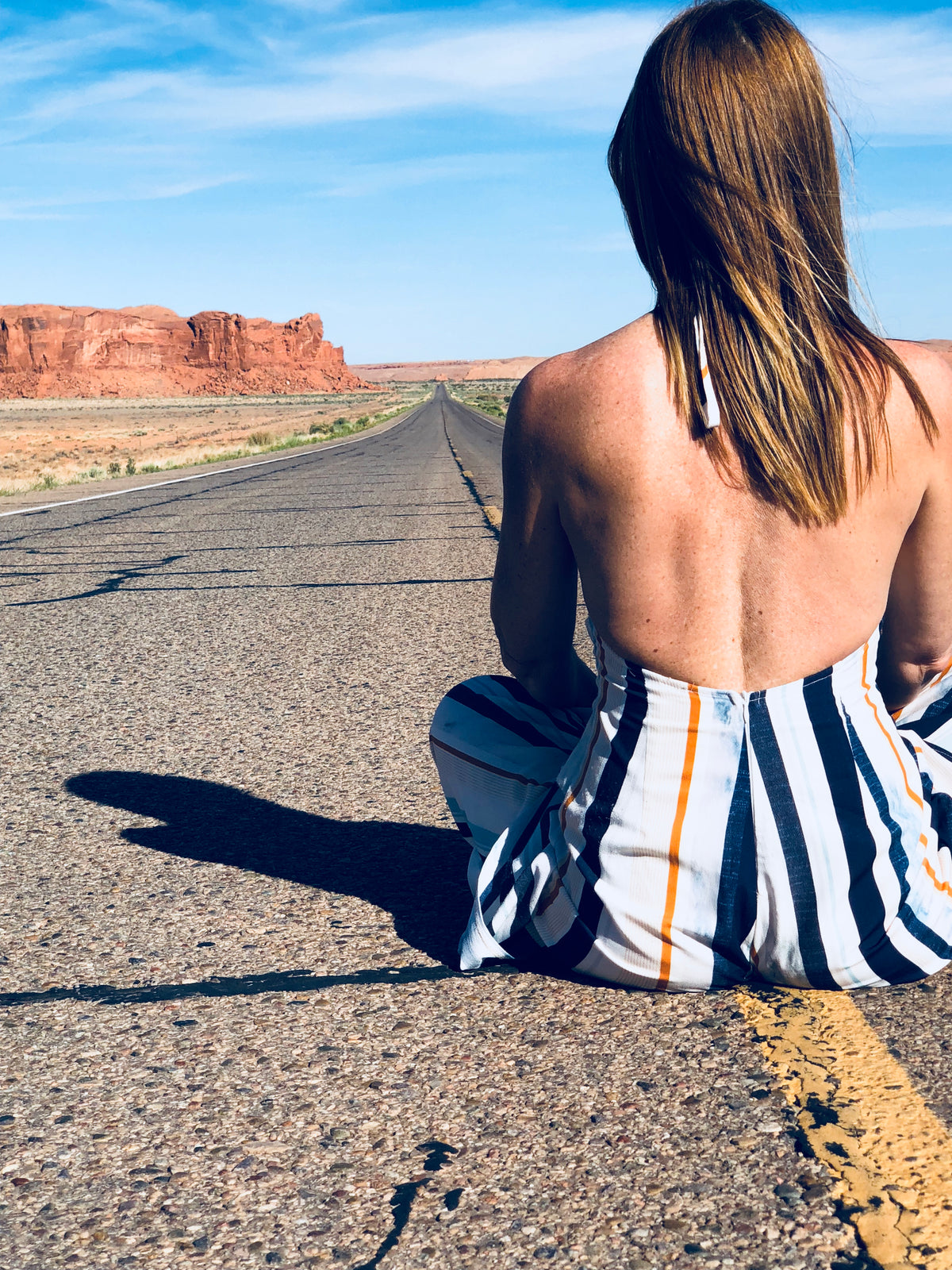a woman sat in the middle of a highway through the desert