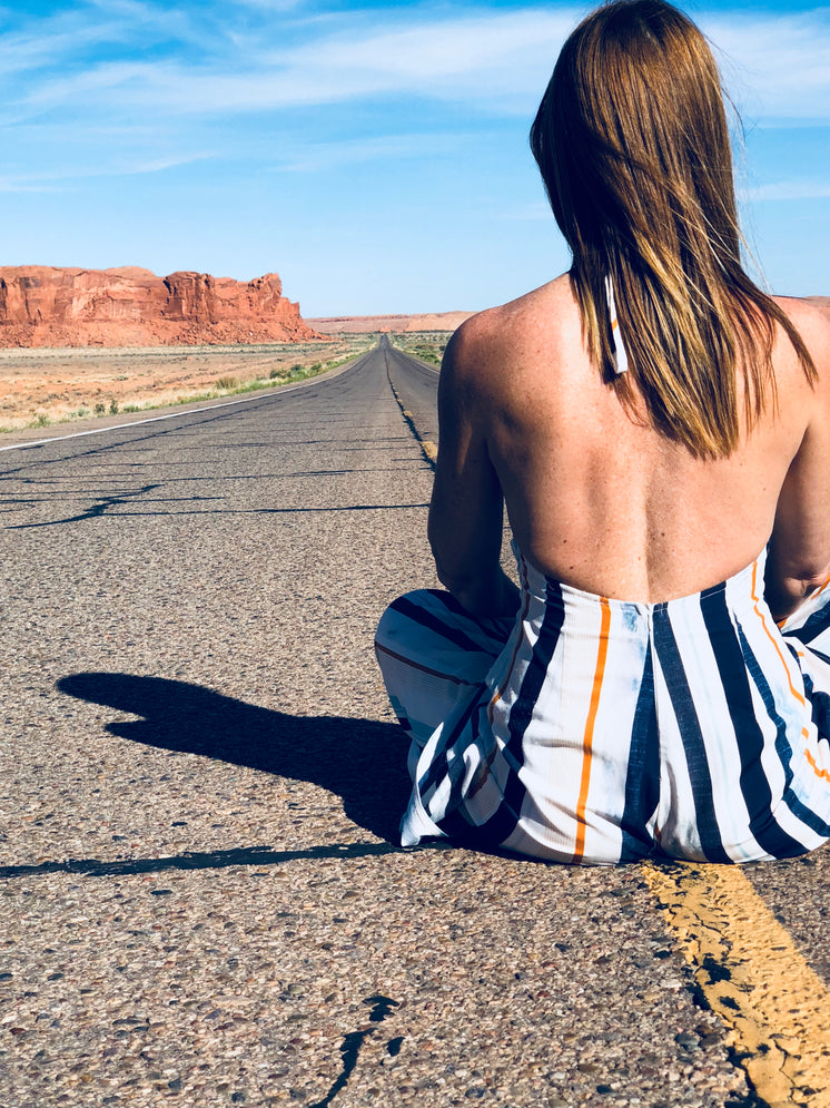 A Woman Sat In The Middle Of A Highway Through The Desert