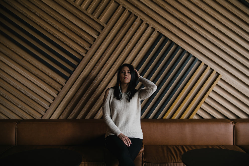 A Woman Sits Against Large Wooden Wall
