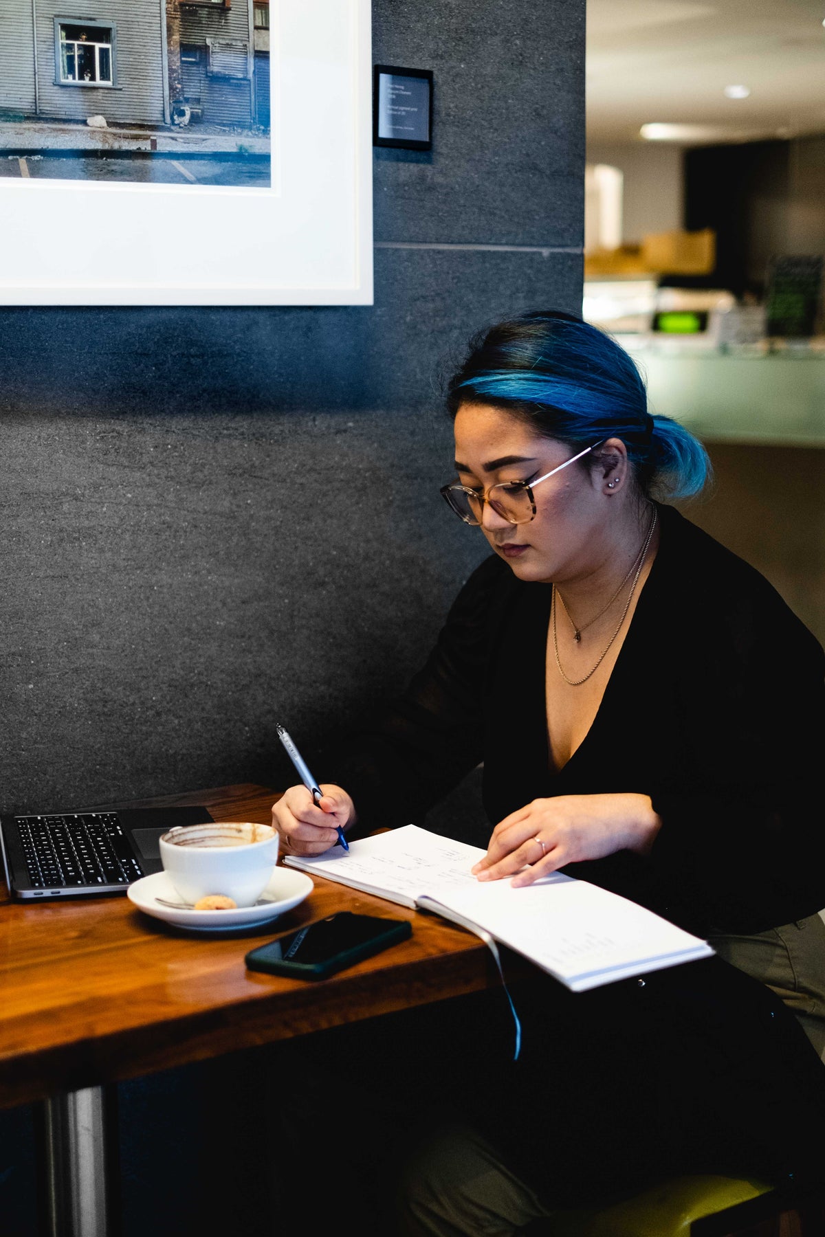 a woman sits alone in a coffee shop writing
