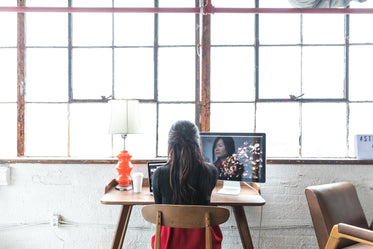 a woman sits at her desk in front of a large window