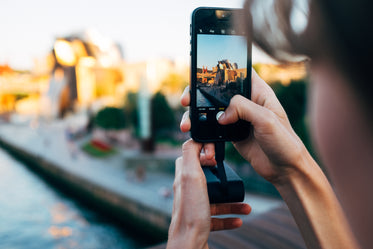 a woman snaps a large aluminium building on her phone