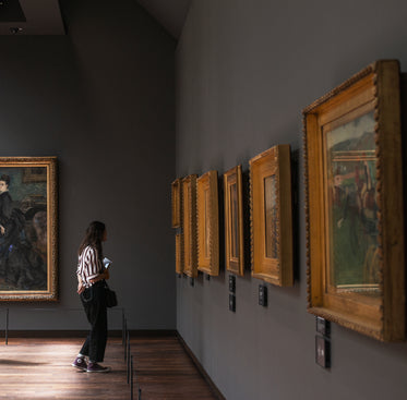 a woman stands in an art gallery in front of paintings