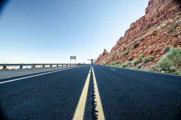 a woman stands in the middle of a desert highway