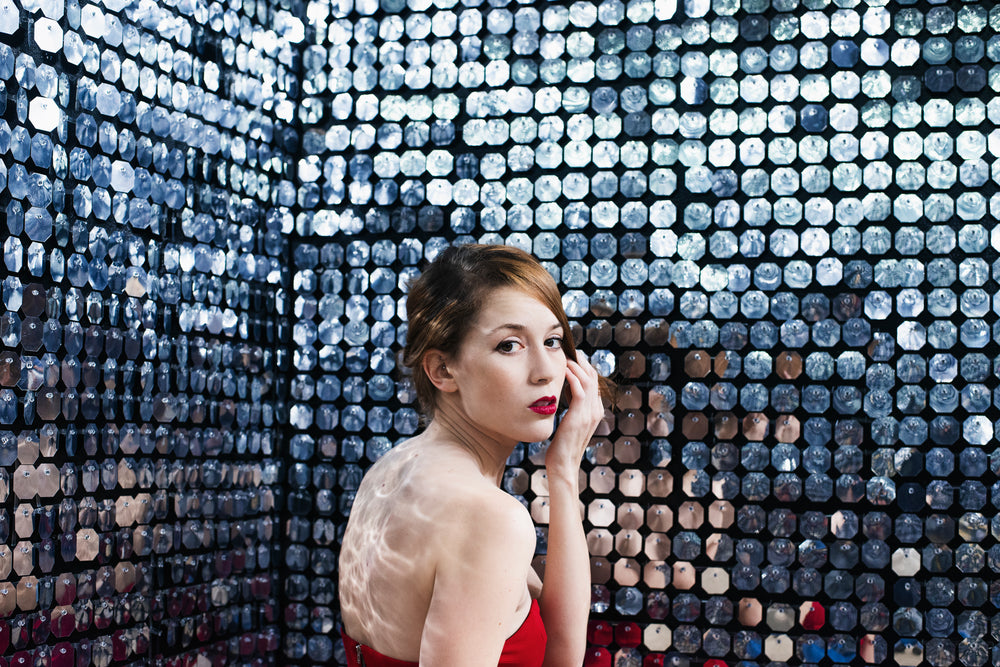 a woman strokes hair from face to stare back over her shoulder