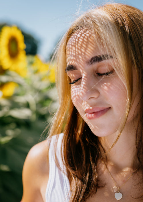 a woman with closed eyes surrounded by sunflowers