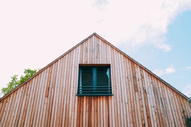 a wooden house with attic window under cloud-studded sky