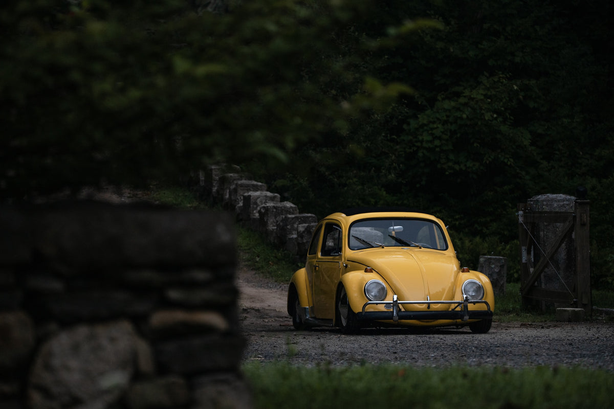a yellow car parked on a lush country road