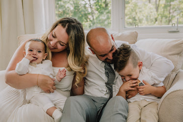 a young family sitting together on a beige couch