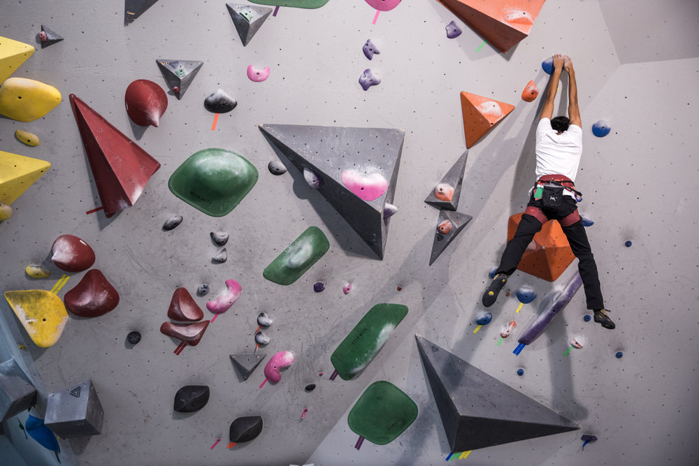 a young rock climber hangs from a wall