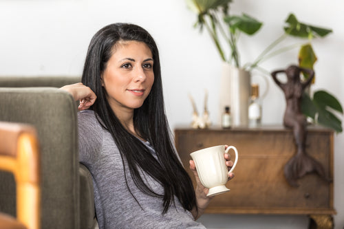 a young woman leans back on a couch with a coffee