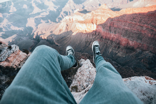 adveturer legs dangle over canyon edge