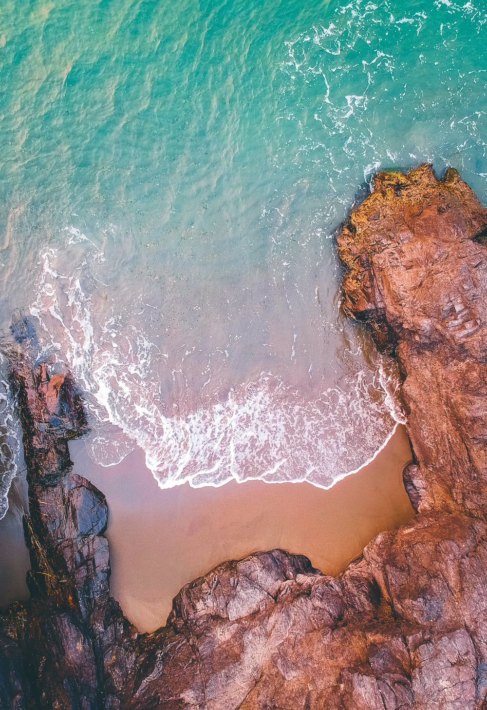 aerial view of sea rolling into a rocky shore