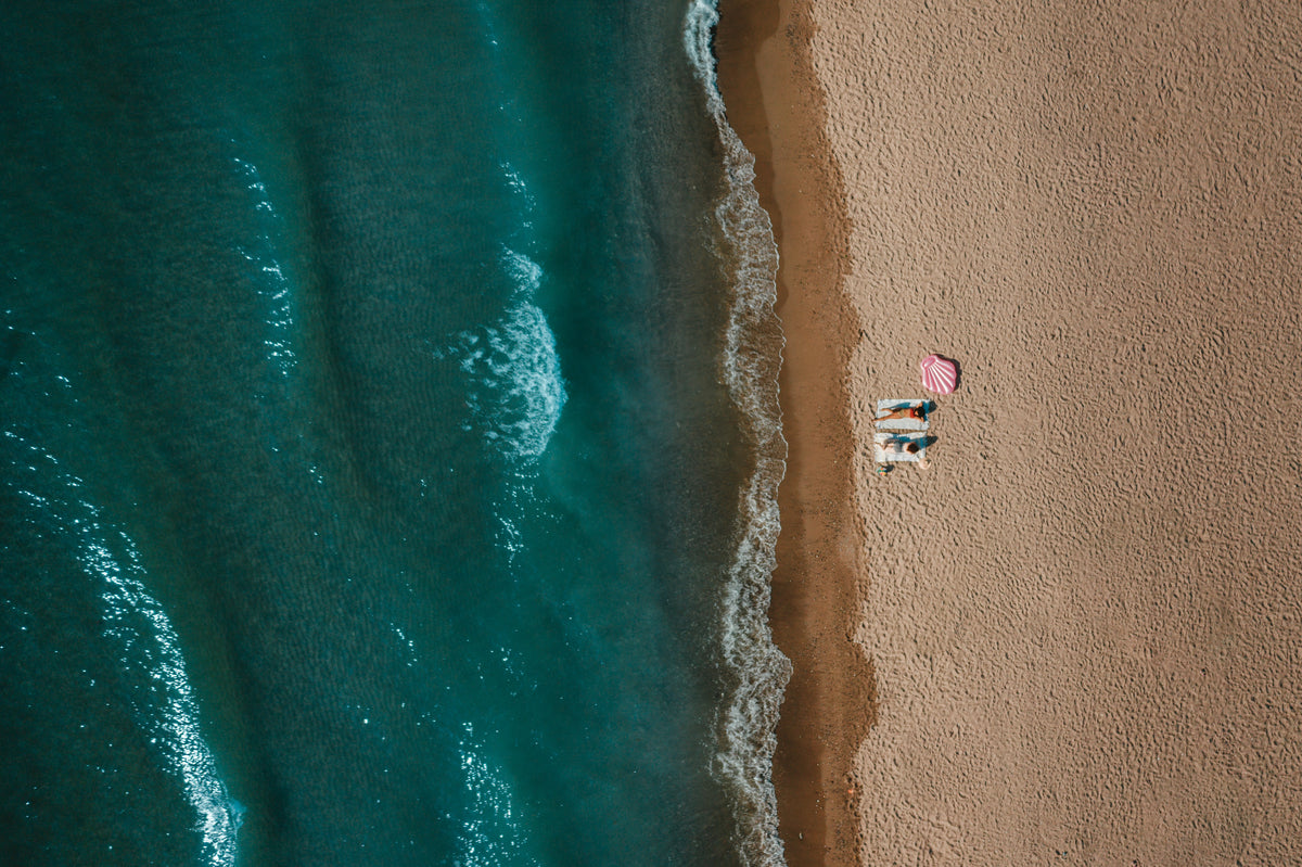 aerial view of two women sitting on sandy beach