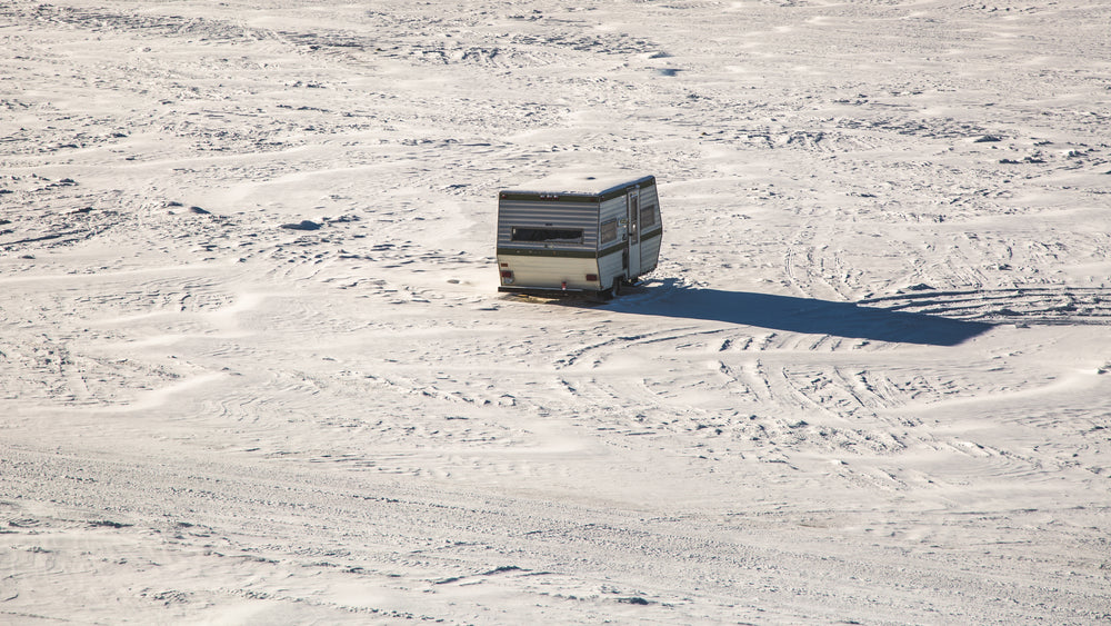 an abandoned camper trailer parked in an open snow-covered field