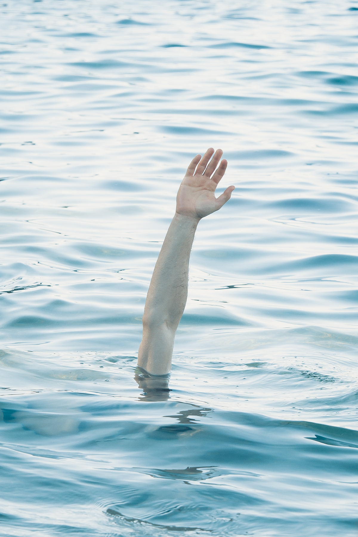 an arm reaches up over the blue water