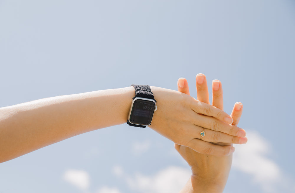 an arm with a smart watch against a blue sky