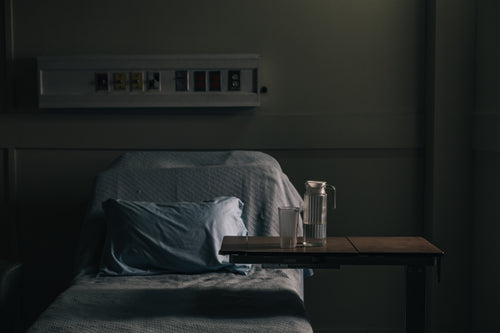 an empty hospital bed in a darkening room