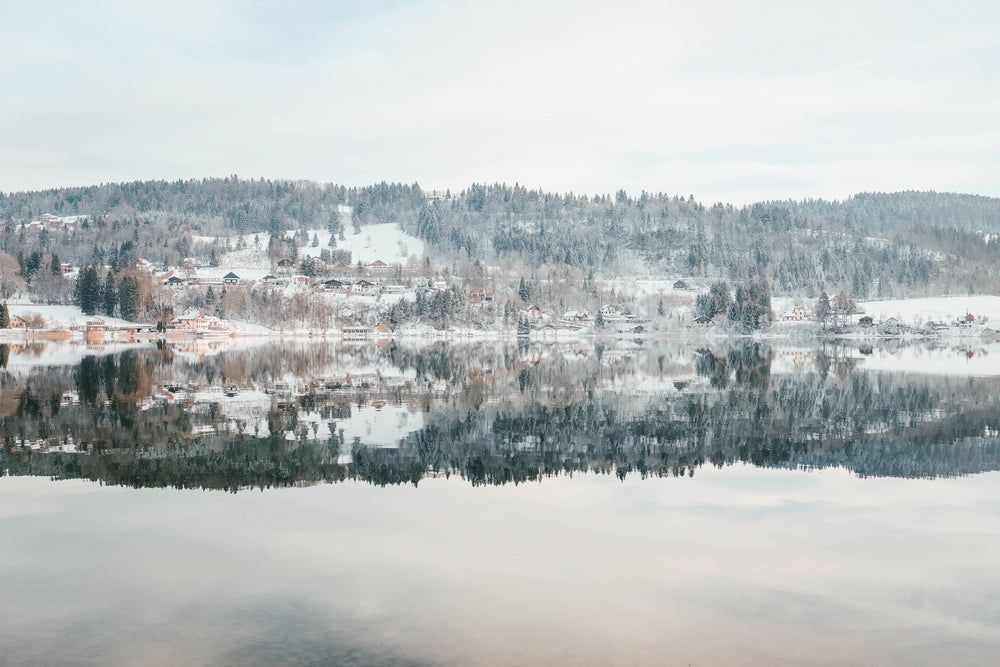 an icy lake under snowy and snowy hills under frosty sky